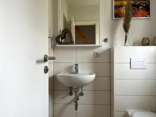 a white bathroom with a sink and a mirror at Ferienhaus am Saaler Bodden in Beiershagen