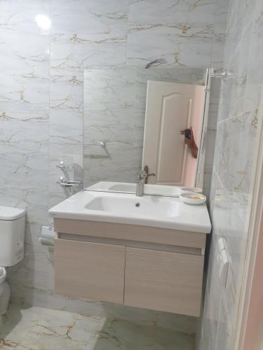 a white bathroom with a sink and a mirror at Appartement Meublé AIN SEBAA in Aïn Sebaa