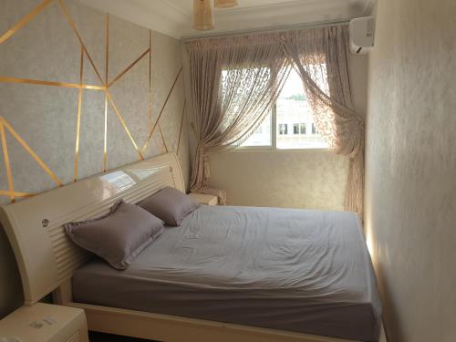 a small bedroom with a bed and a window at Appartement Meublé ALHADIKA in Aïn Sebaa