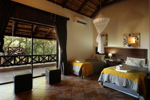 a bedroom with two beds and a large window at Eden Safari Country House in Marloth Park