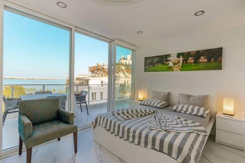 sypialnia z łóżkiem i krzesłem oraz dużymi oknami w obiekcie Antalya Konyaaltı Full View w mieście Antalya