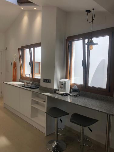 a kitchen with a counter with two stools and two windows at Antiga Biblioteca in Solsona
