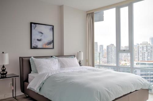 a bedroom with a white bed with a large window at Habitas in Vancouver