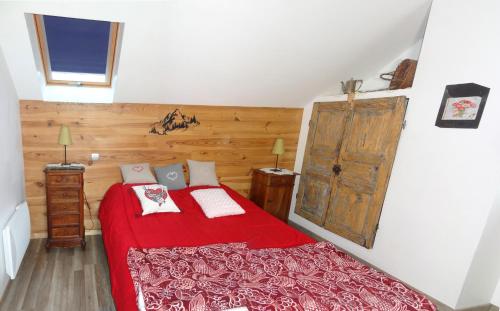 a bedroom with a red bed and a wooden door at Gite de Champ Chaulier in Crots