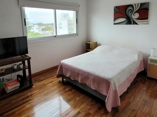 a bedroom with a bed and a flat screen tv at Luminoso Monoambiente in La Plata