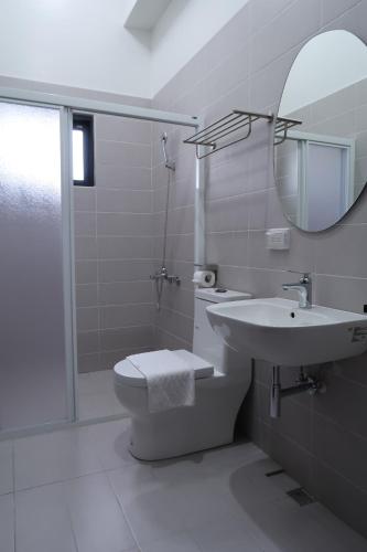 een badkamer met een toilet, een wastafel en een spiegel bij SUNME Inn in Magong