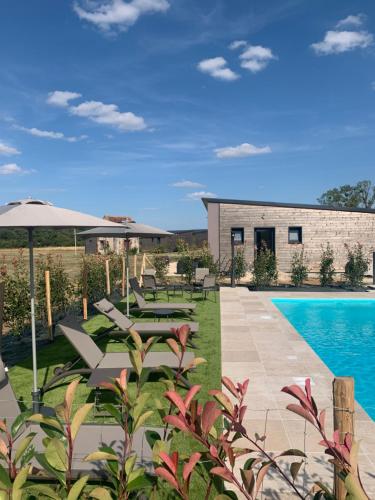 a patio with chairs and an umbrella next to a pool at Cottages du Golf Fleuray-Amboise in Cangey
