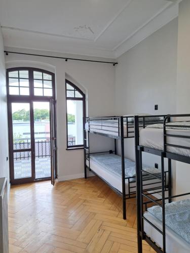 a room with three bunk beds and a wooden floor at Gingerbread Hostel in Toruń