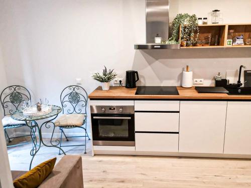 a kitchen with white cabinets and a table and a stove at Three By The Sea apartments at Albatross Home in Ķesterciems