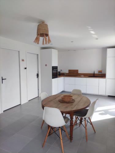 - une cuisine avec une table en bois et des chaises blanches dans l'établissement maison neuve 4 ou 5 personnes Kerguen, à Plobannalec-Lesconil