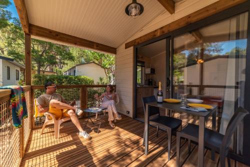 a man and a woman sitting on the porch of a house at Camping La Pinède Enchantée in Argelès-sur-Mer