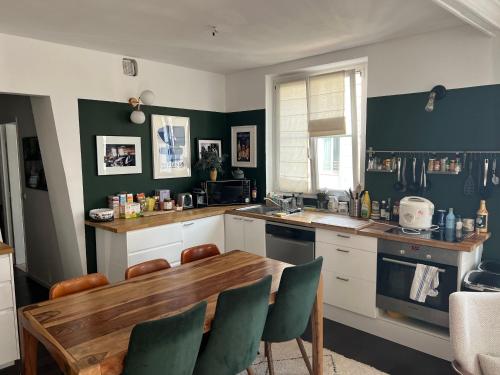 - une cuisine avec une table en bois et des murs verts dans l'établissement chambre privée dans superbe appartement parisien !, à Paris