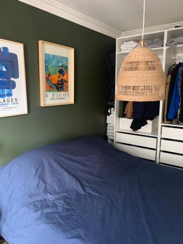 - une chambre avec un lit bleu et un mur vert dans l'établissement chambre privée dans superbe appartement parisien !, à Paris