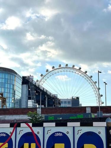 a ferris wheel in the background of a city at Spacious 2Bed/2Bath Flat next to London Eye in London