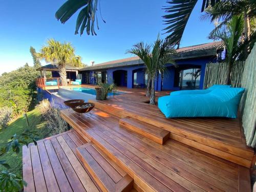 a wooden deck with a swimming pool and a house at Amasundu Beach House Trafalgar in Southbroom