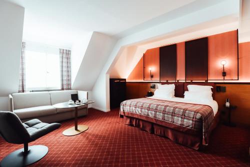 a hotel room with a bed and a chair at Hôtel Les Jardins de Deauville in Saint-Martin-aux-Chartrains