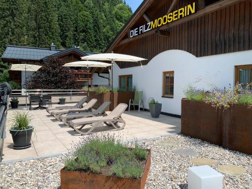 a patio with chairs and umbrellas in front of a building at Die Filzmooserin - Apartments in Filzmoos, Filzmoos Card inklusive in Filzmoos