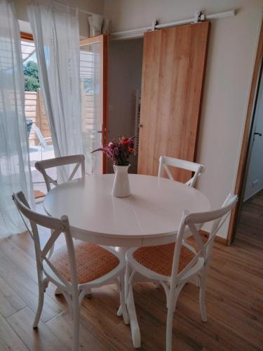 d'une table blanche et de deux chaises avec un vase. dans l'établissement Les Granges des Petits Couleurs, aux Épesses