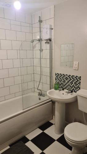 a bathroom with a tub and a toilet and a sink at Alexandra Park Apartments in Belfast