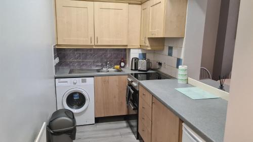 a small kitchen with a washing machine and a sink at Alexandra Park Apartments in Belfast