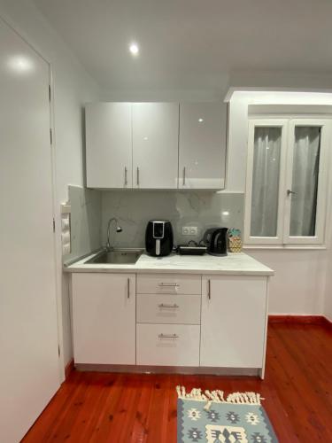 a kitchen with white cabinets and a sink at Corfu Port Art Studios in Agios Rokkos