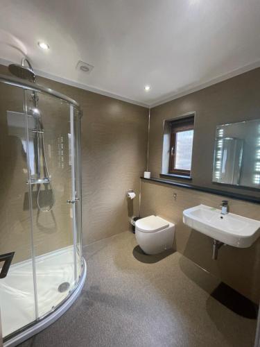 a bathroom with a shower and a toilet and a sink at Redwood Lodge in Penrith
