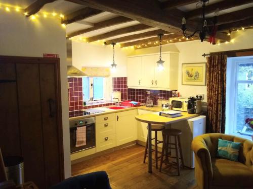 里士滿的住宿－Rose Cottage. Richmond, North Yorkshire，一间厨房,内设白色橱柜和一张桌子