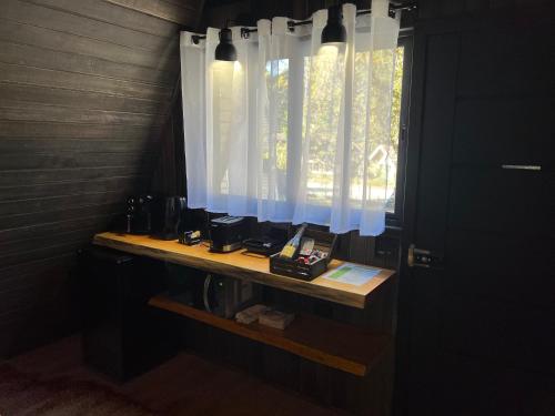 a bathroom with a window with white curtains at Chalé Villa Nature in Campos do Jordão