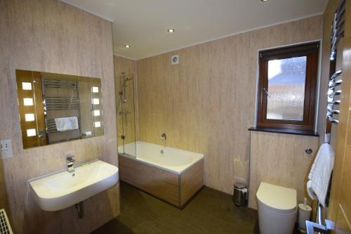 a bathroom with a sink and a tub and a toilet at Aikbeck Lodge in Penrith
