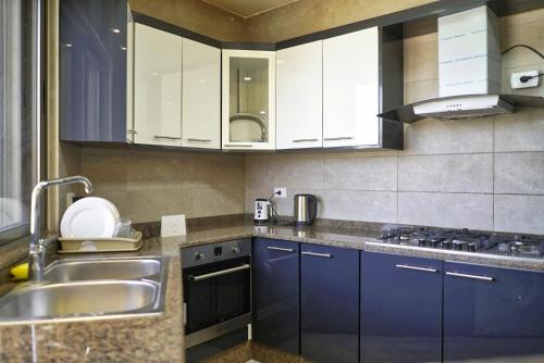 a kitchen with blue cabinets and a sink at شقة فاخرة و واسعة من 4 غرف مع وسائل الراحة الحديثة Spacious 4-Room Apartment with Modern Amenities in Amman