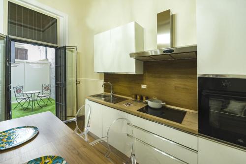 a kitchen with white cabinets and a sink and a table at Appartamento Martoglio - Casa Vacanze - in Catania