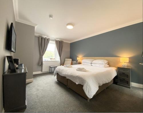 1 dormitorio con 1 cama grande y pared azul en The Anchor Inn, en Garelochhead