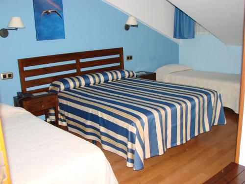 a bedroom with two beds and a blue wall at Hotel Bufon de Arenillas in Vidiago