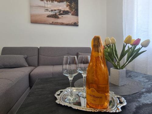 a bottle of champagne and two wine glasses on a table at Lady Di apartments in Kaštela