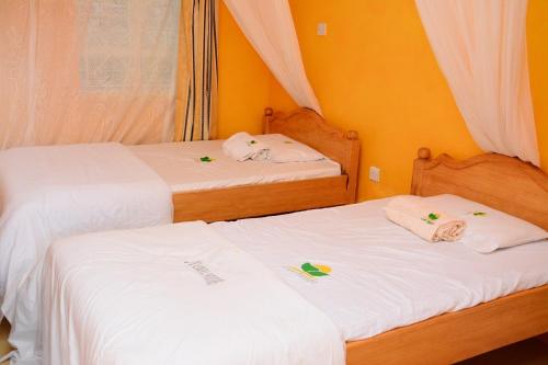 2 bedden in een kamer met witte lakens bij New Green Pastures Guest House in Eldoret