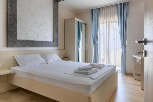 een slaapkamer met een groot bed en handdoeken bij Hotel Maksim in Herceg-Novi