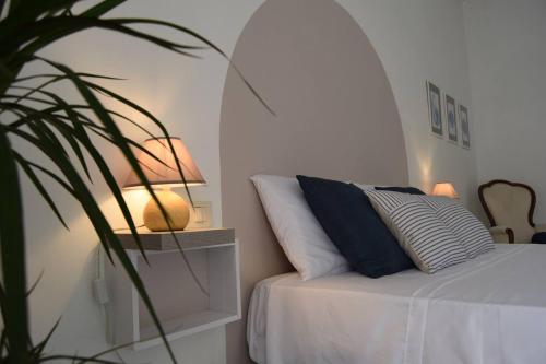 Un dormitorio blanco con una cama y una planta en Meridiana case al mare centro, en Mattinata