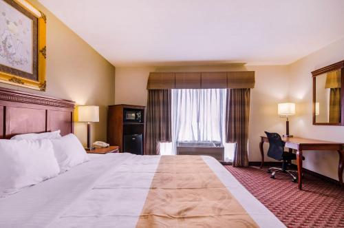 a hotel room with a large bed and a desk at Quality Inn & Suites in Carthage