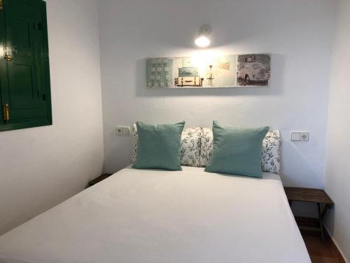 1 dormitorio con cama blanca y almohadas azules en Viviendas Ferrer - Can Joan Andrauet, en Sant Francesc Xavier