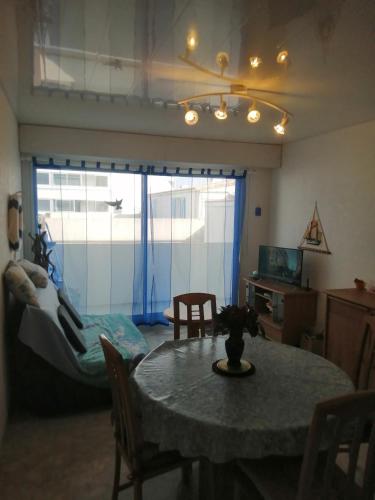een woonkamer met een tafel en een slaapkamer bij appartement saint hilaire de riez 85270 in Saint-Hilaire-de-Riez
