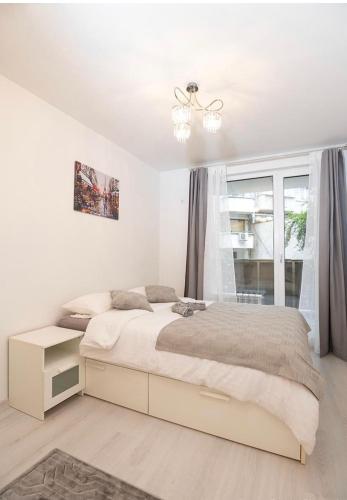 a white bedroom with a bed and a window at Top Central Apartment & Free Parking in Sofia