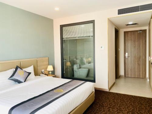 a bedroom with a large bed and a glass window at Hera Luxury Hotel in Ho Chi Minh City