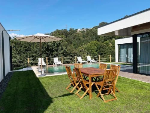 a table with chairs and an umbrella next to a pool at Casas da Veiga in Braga
