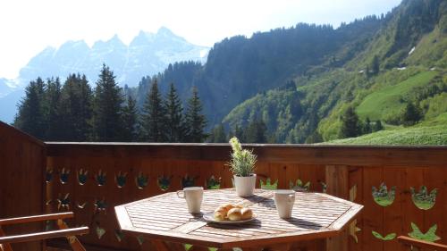 a table on a balcony with a view of mountains at Hotel L'Etable in Les Crosets