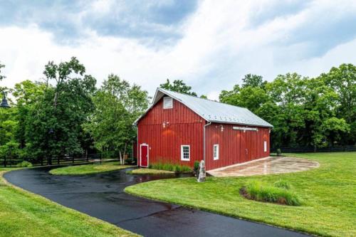 a red barn in a field with a road at LUX HOME 5 BD, GIFT CARD, GAME ROOM, and more! in Ashburn