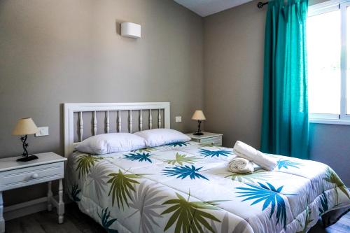 a bedroom with a bed with a tropical print on it at La Casita del Sur, Abades in Abades