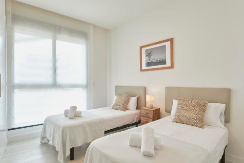 two beds in a room with a window at Terraza de Alborán in Málaga