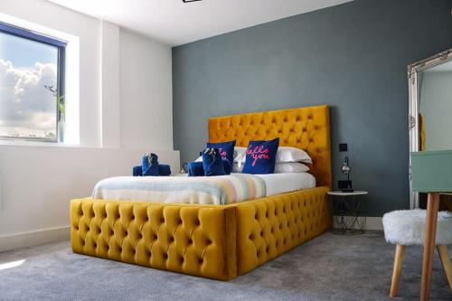 a bedroom with a large yellow bed with blue pillows at Funky Flat - City Centre - Free Parking in Norwich