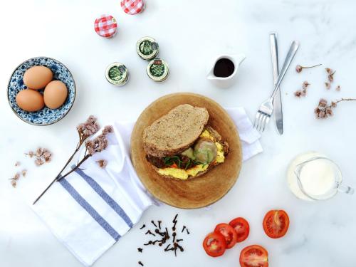 a white table with a sandwich and eggs on it at Morrissey Hotel in Jakarta