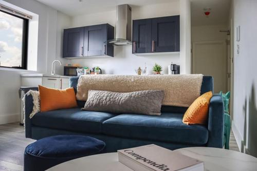 a living room with a blue couch and a kitchen at Funky Flat - City Centre - Free Parking in Norwich